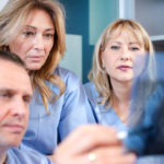 Group of doctors and nurses looking to and discussing x-ray image at clinic.